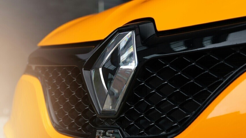 Renault vehicle badge on front grille of a yellow company car.
