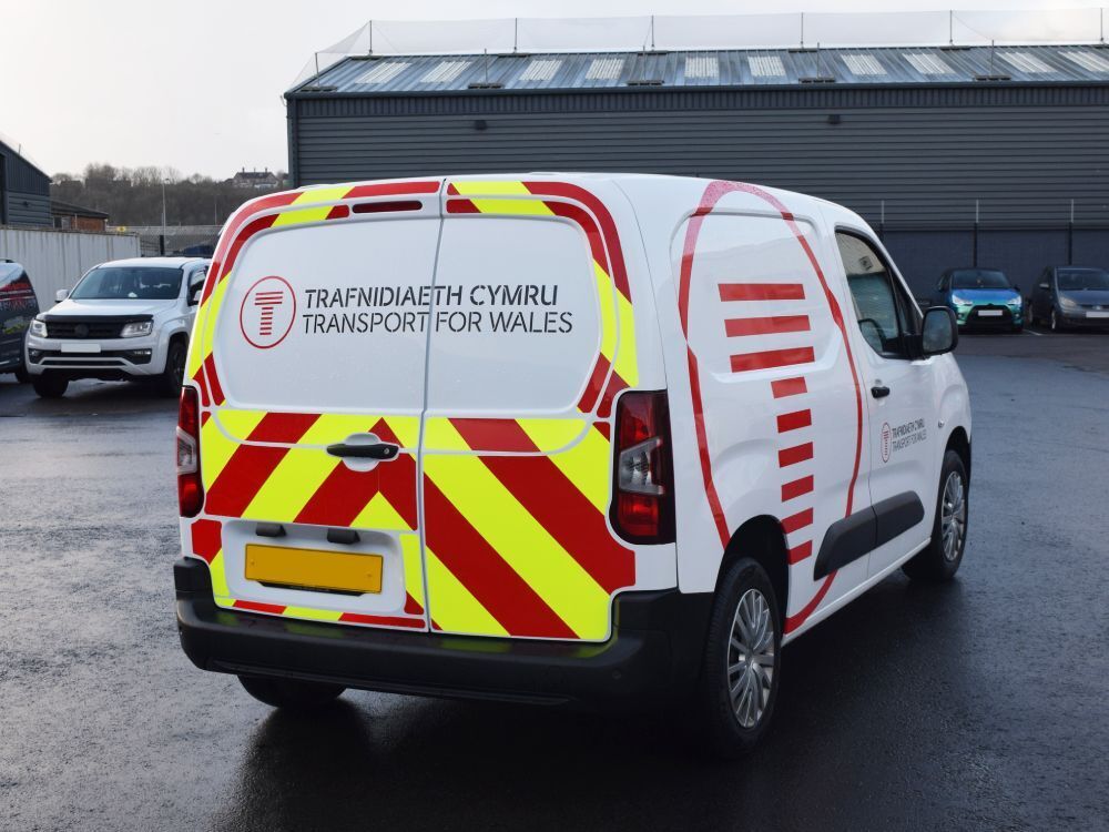 Reflective chevron safety chapter 8 graphics installed on the back of a white company Citroen Berlingo van.