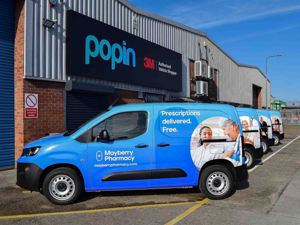 Fleet of Peugeot Partner vans with matching Mayberry Pharmacy blue vehicle wraps and vinyl graphics outside Popin in Cardiff.