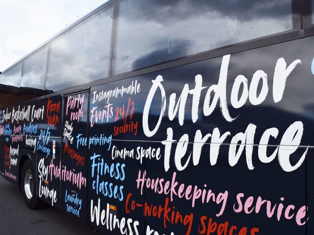 Close up of colourful promotional vinyl graphics on side of navy Mercedes Tourismo company coach for Zenith Students.