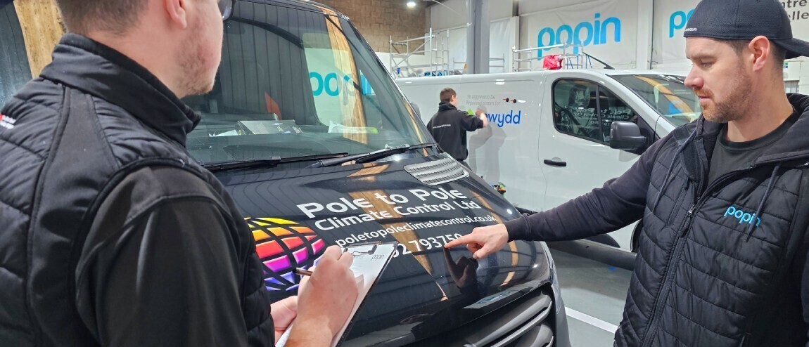 Vehicle wrap installers inspecting vinyl graphics on a company van
