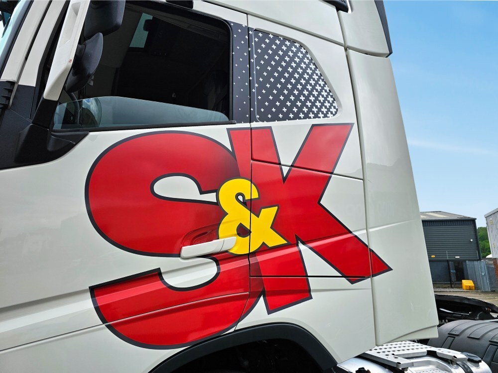Close up of branded vehicle graphics on a white Volvo lorry.