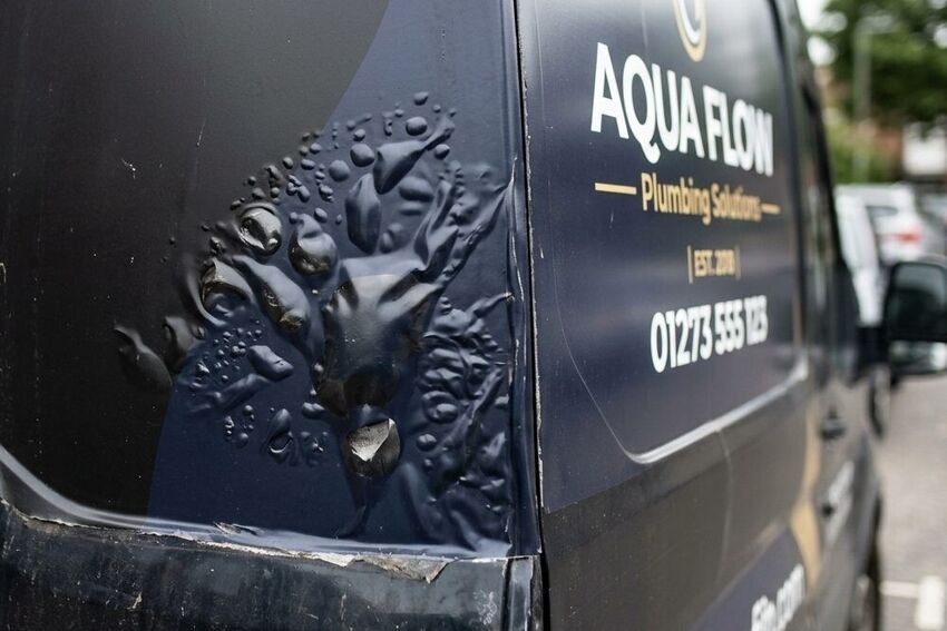 Air bubbles trapped underneath low quality vehicle vinyl wrap on company van.