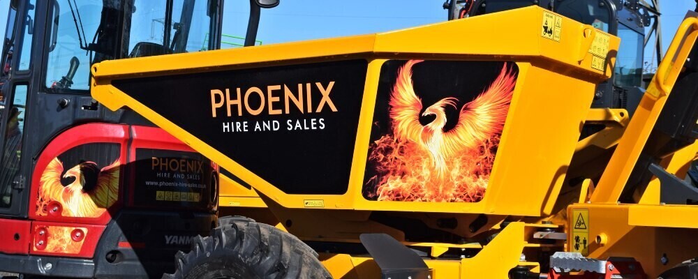 Yellow dumper with plant machinery vinyl graphics applied for branding on a construction site.