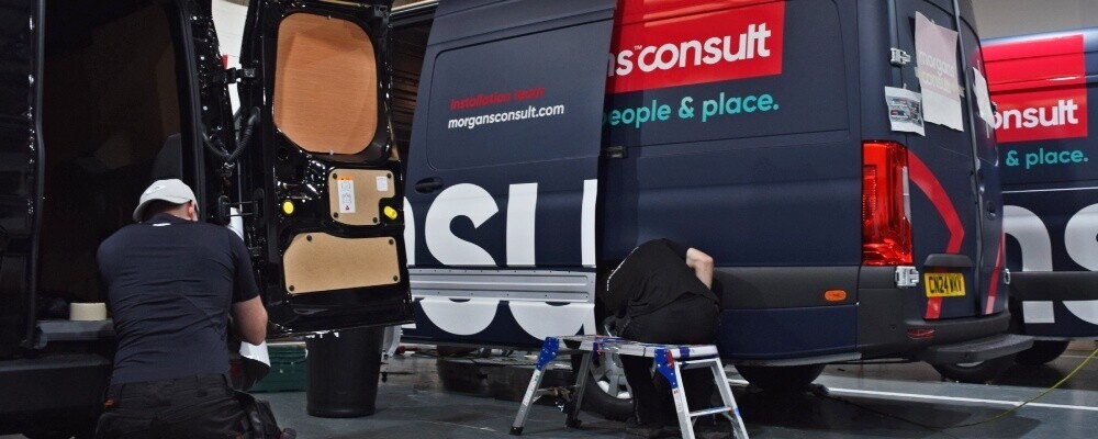 Popin Graphics technicians applying vinyl wrap to commercial fleet vans.