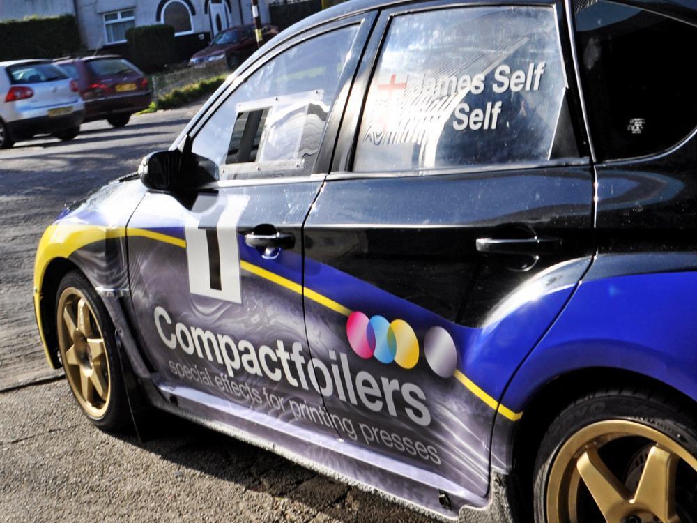 Side of Subaru Impreza B13 company car with vehicle wrap and branded graphics.