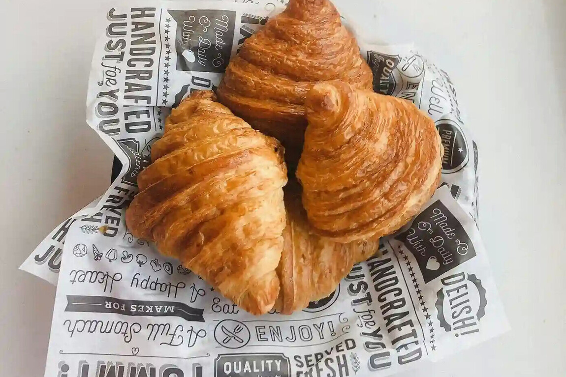 A photo of croissants laying on printed paper