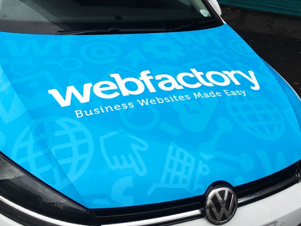 Blue bonnet vehicle wrap with white graphics on Volkswagen Golf company car.