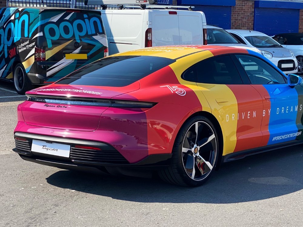 Rear end of colourful Porsche Taycan Turbo in 75th anniversary motorsport livery