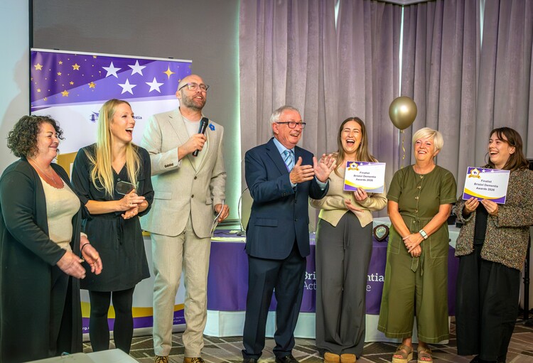 Your Care team celebrating on stage at the Bristol Dementia Action Alliance Awards 2026, holding finalist certificates alongside other attendees.