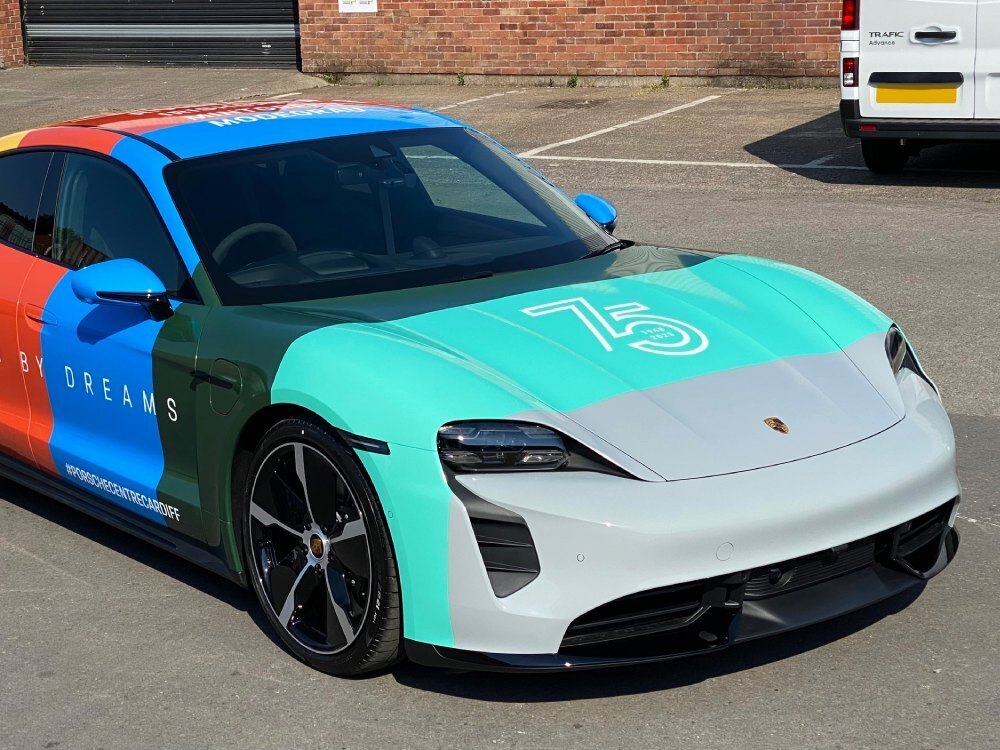 Front of Porsche Taycan Turbo in colourful motorsport wrap celebrating 75th anniversary