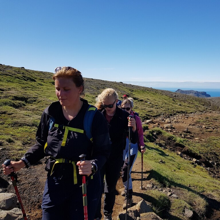 Guided hikers climbing toward the ridge above Hornvík Bay in Hornstrandir, Iceland
