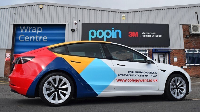 Partial vehicle wrap and branded vinyl graphics on Tesla Model 3 company car outside Popin in Cardiff.