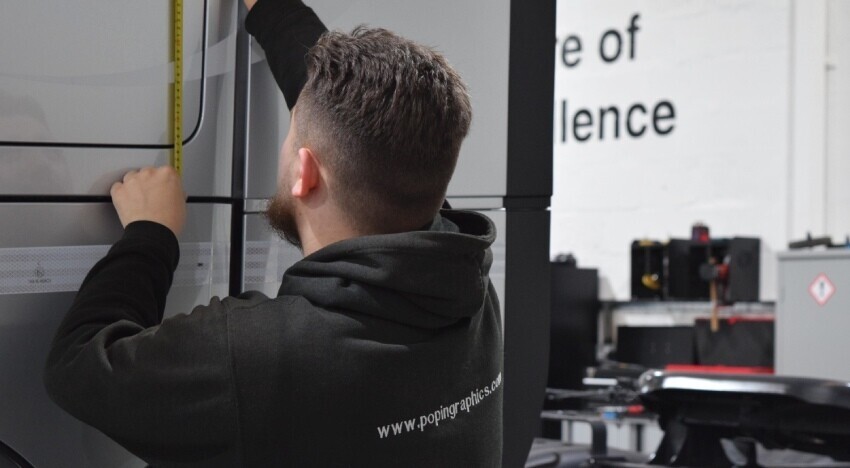 Popin vehicle wrap technician measuring a Dennis lorry during installation.
