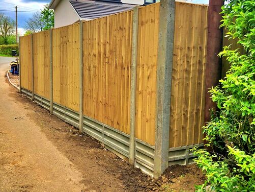 This image showcases a newly installed wooden fence supported by concrete posts and gravel boards at the base, providing both durability and a clean aesthetic. The design is practical and ensures stability, while the natural wood adds warmth and blends well with the surrounding greenery.

This type of fencing is ideal for privacy and defining property boundaries.