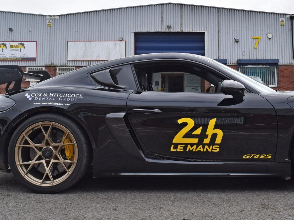 Black company Porsche GT4 RS with branded vinyl graphics.