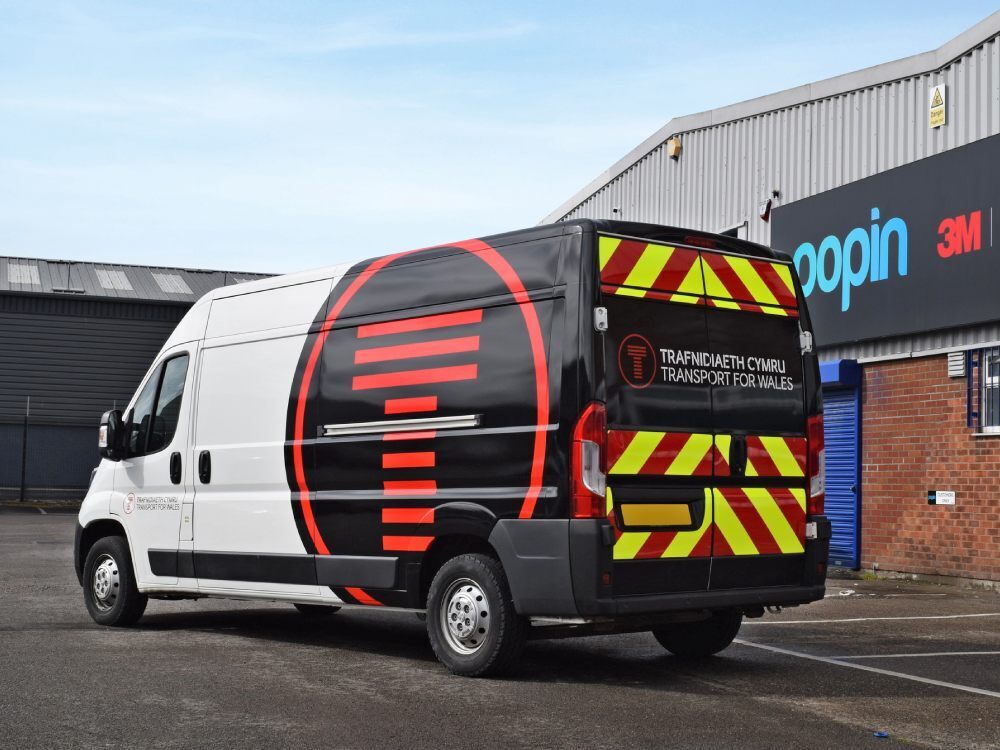 White Peugeot Boxer van with partial vehicle wrap and chevron vinyl graphics on rear.