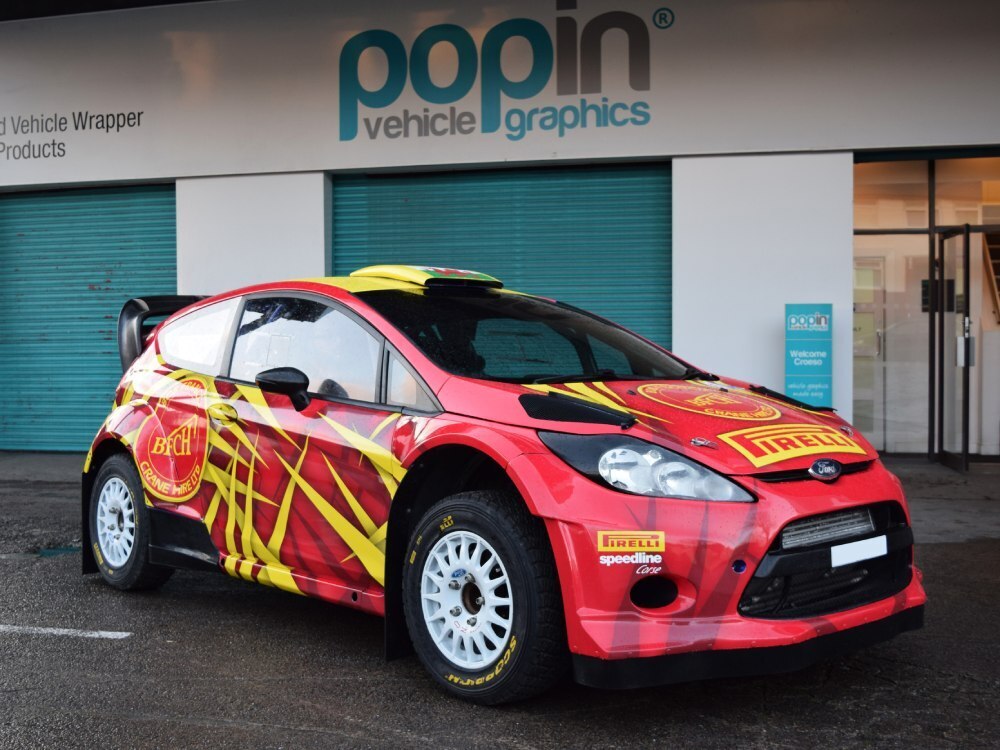 Red and yellow motorsport livery on a Ford Fiesta R5