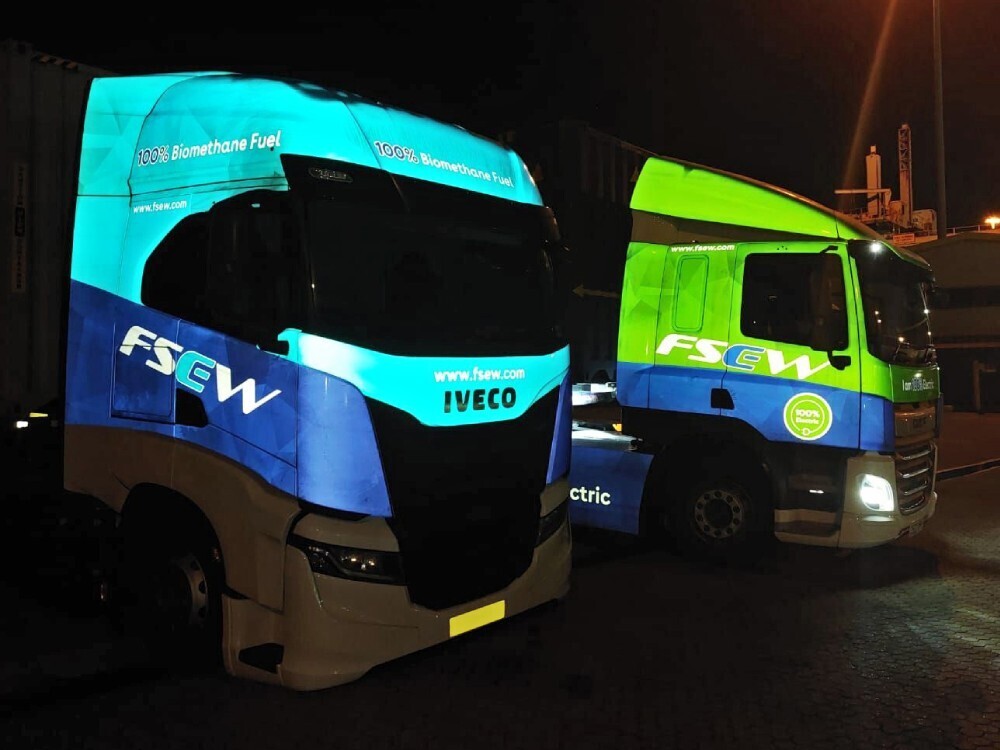 Bright reflective vehicle wraps on Iveco trucks at night.