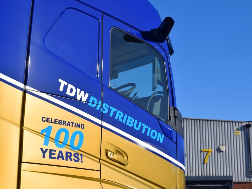 Blue and gold vehicle livery and vinyl graphics installed on a Volvo lorry cab.