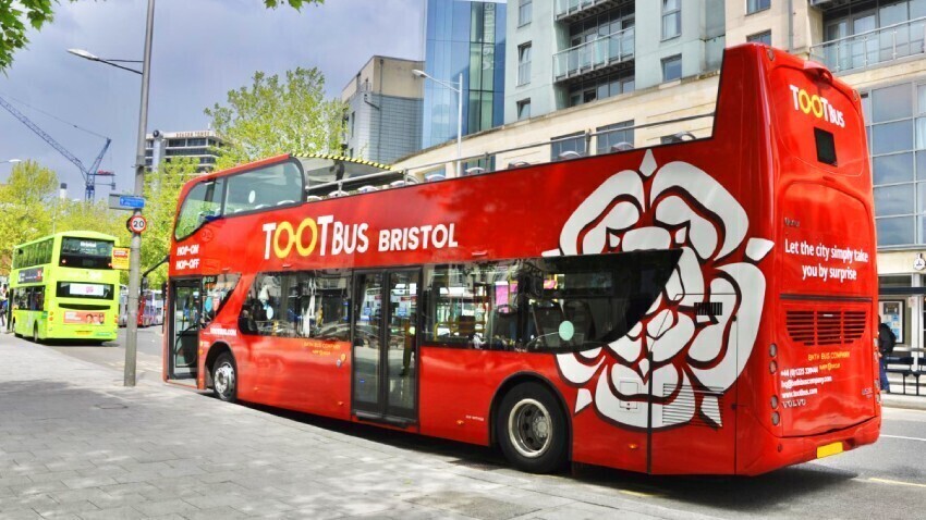 Red UNVI Urbis Bristol Tootbus open top tour bus with branded promotional vinyl graphics.