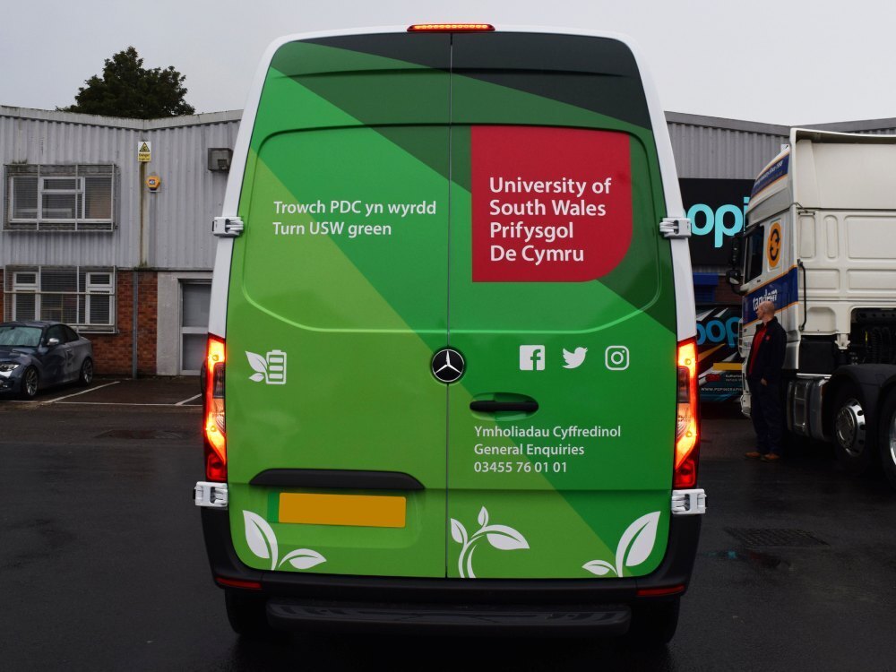 Rear of Mercedes-Benz eSprinter electric van with University of South Wales branded wrap outside Popin in Cardiff.