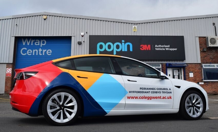 A leased Tesla car with removable partial vehicle wrap and vinyl graphics parked outside Popin in Cardiff.