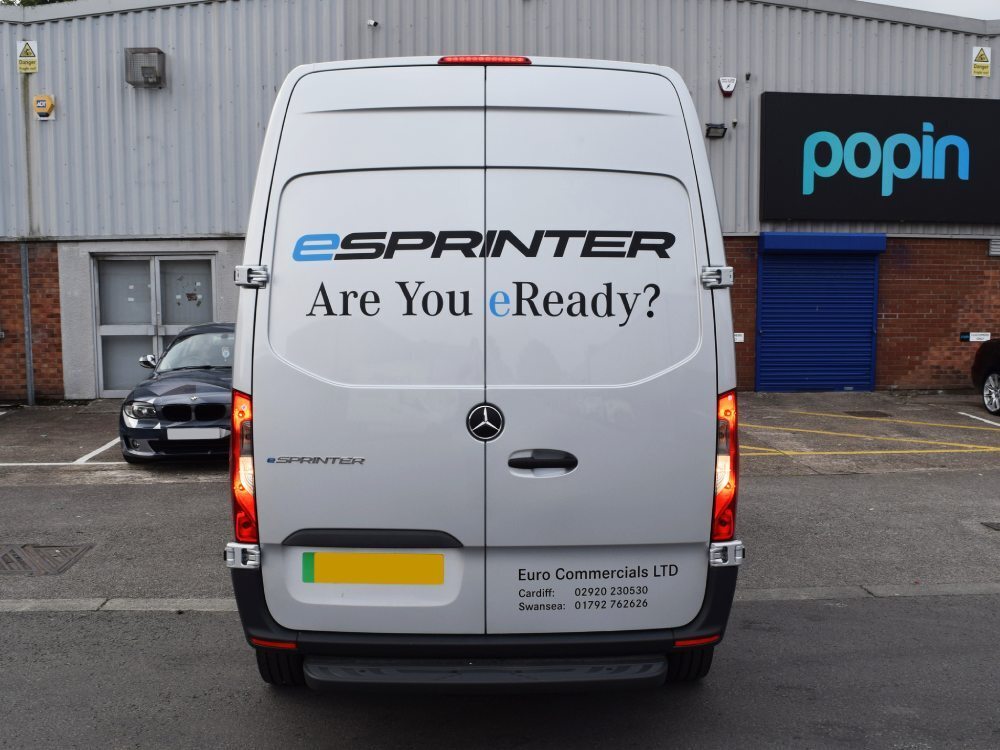 Rear end of silver Mercedes-Benz eSprinter with company promotional graphics outside Popin in Cardiff.