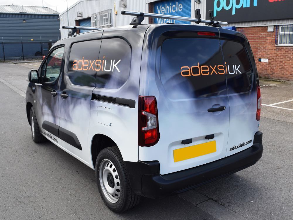 Rear view of company Peugeot Partner van with full vehicle wrap.