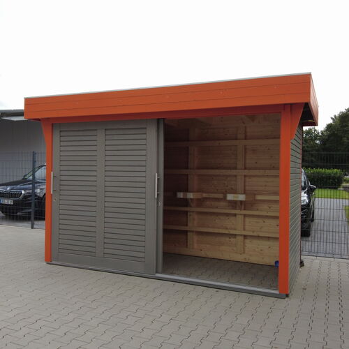 Contemporary timber storage building with a flat roof, featuring a bold orange frame that contrasts with sleek gray slatted sliding doors. The design includes an open side section with exposed wooden shelving, providing easy access and functional storage. Built on a durable paved base, this structure is ideal for both residential and commercial use. Its modern aesthetic and practical features make it a versatile addition to any setting. Designed and installed by Forever Timber and supplied by Bertsch HolzBau, this building combines innovative design with expert craftsmanship for a durable and stylish solution.