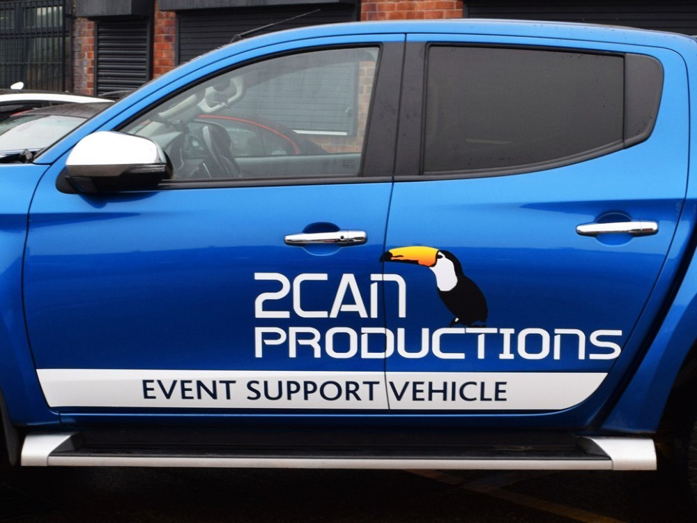 Branded vinyl graphics on door of blue company Mitsubishi L200.