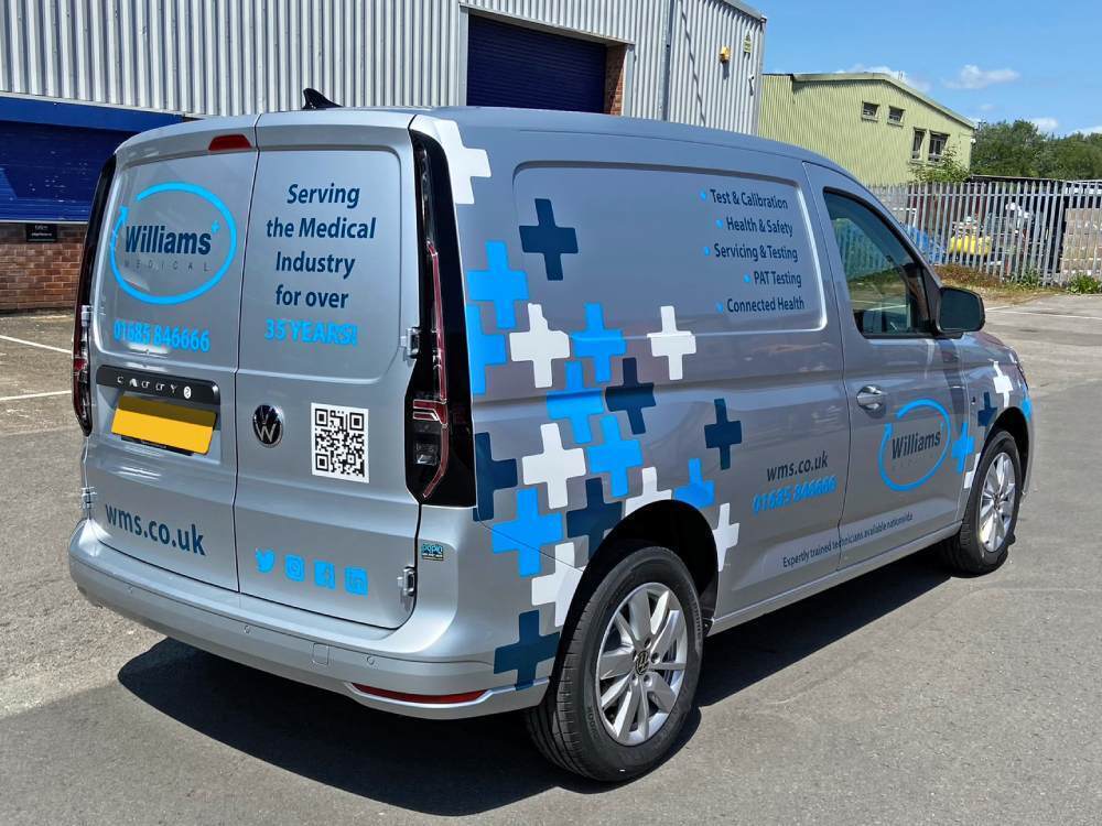 Rear end of silver Volkswagen Caddy with partial van wrap and graphics.