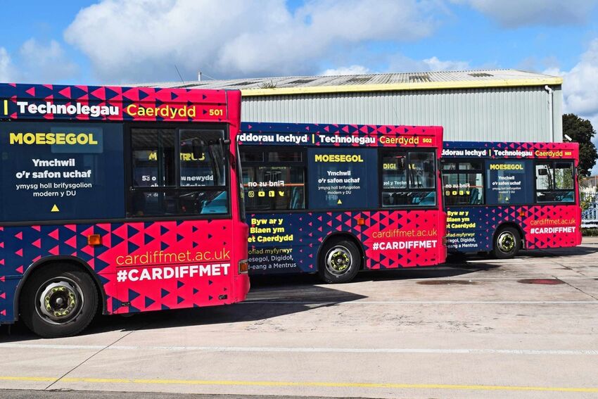 Fleet of Cardiff buses with matching vehicle wraps and commercial graphics.