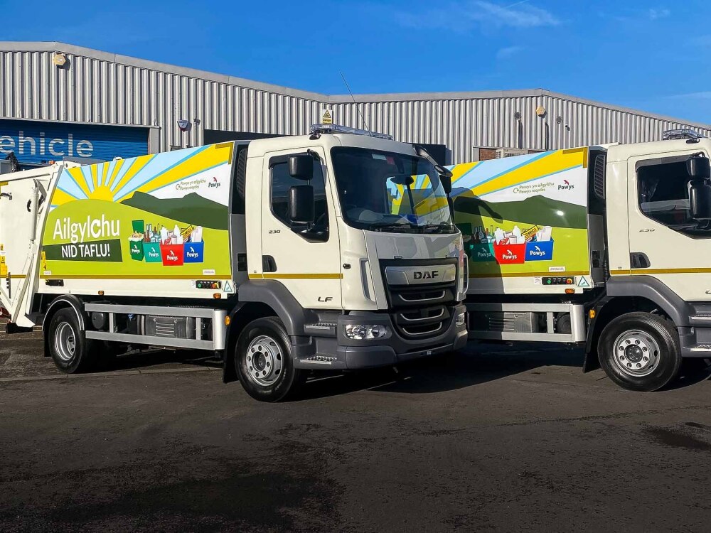 Fleet of DAF LF 230 recycling trucks with branded wraps for Powys County Council.