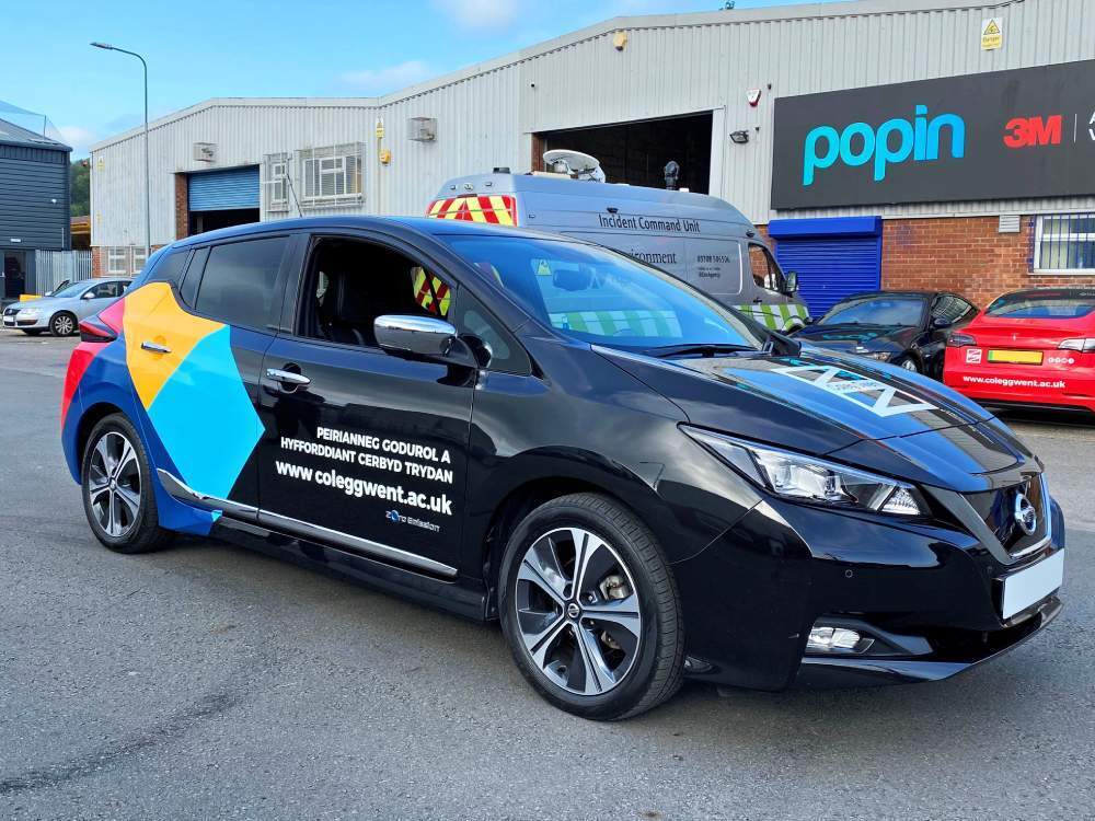 Coleg Gwent branded vehicle livery on Nissan Leaf electric company car outside Popin in Cardiff.