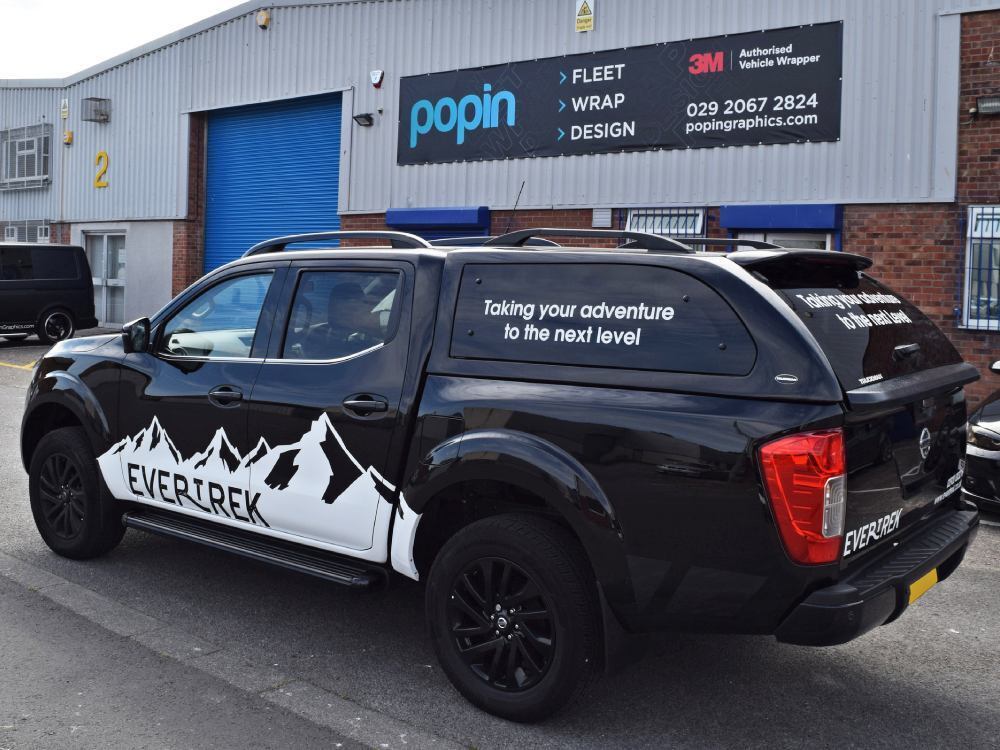 Black company Nissan Navara with branded vinyl graphics outside Popin wrap centre in Cardiff.