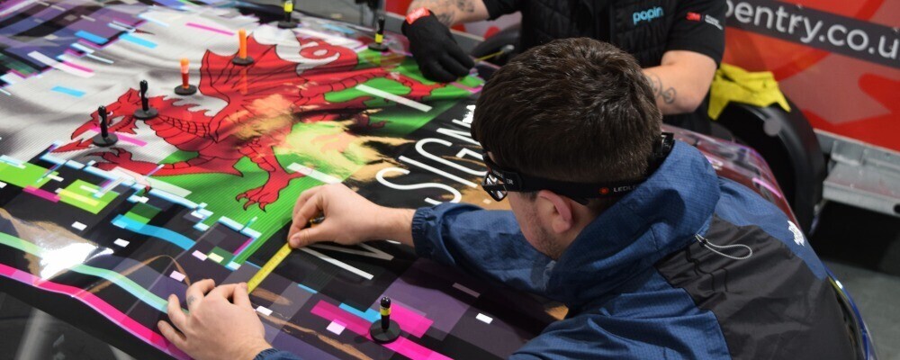 Popin Graphics team installing reflective vinyl graphics onto branded company car.