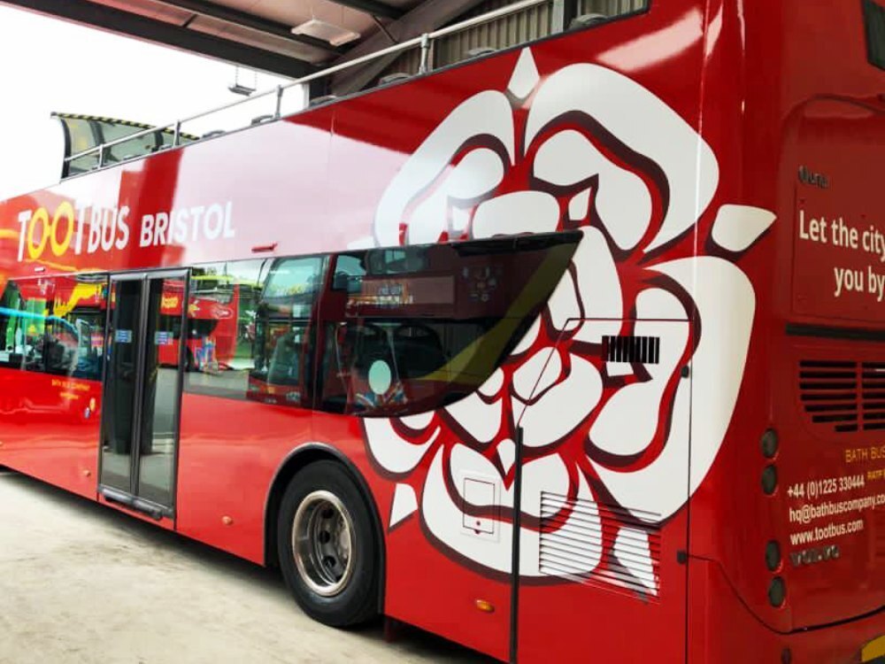 White flower design vinyl graphics on rear end of red UNVI Urbis Tootbus Bristol open top tour bus.