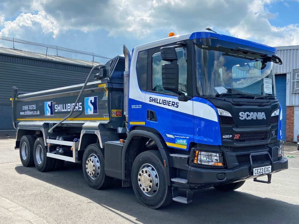 Scania truck with blue vehicle wrap and branded vinyl graphics.
