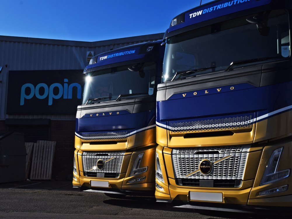 Stunning matching blue and gold vehicle wraps and graphics on two Volvo lorry cabs outside Popin in Cardiff.