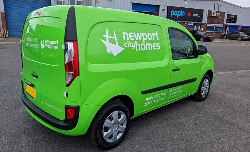 Company electric vehicle with bright green wrap and white branded vinyl graphics out Popin in Cardiff.