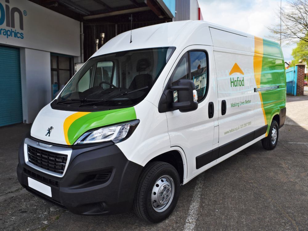 White Peugeot Boxer with partial green and yellow van wrap.