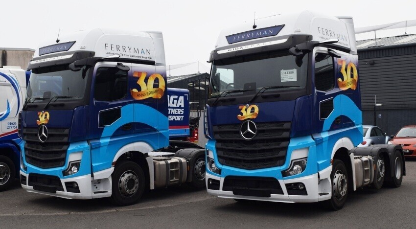 Vehicle liveries on Mercedes logistics lorries parked in a depot.