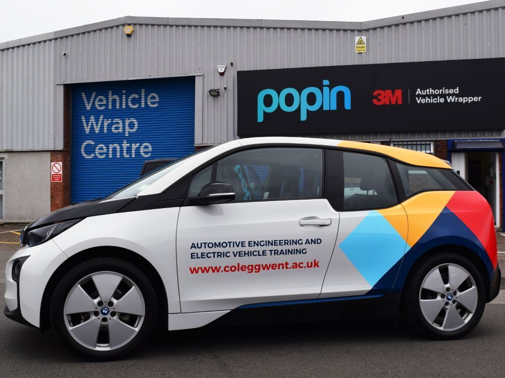 Partial vehicle wrap and branded graphics on BMW i3 electric company car outside Popin in Cardiff.