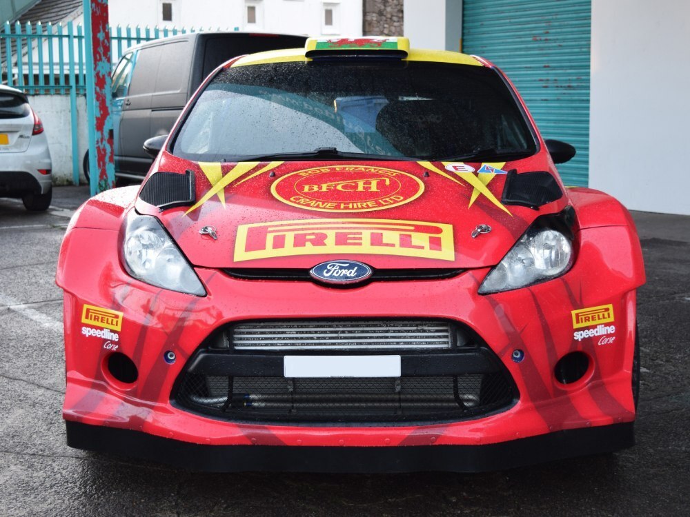 Race vinyl graphics on front end of a red Ford Fiesta R5 rally car