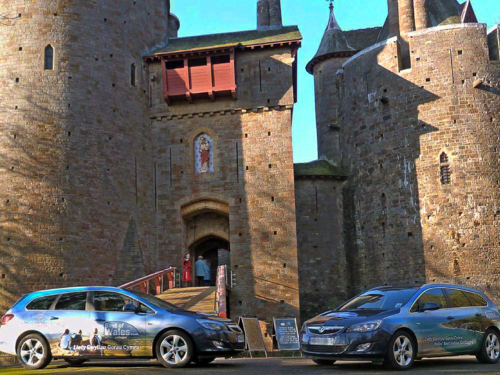 Fleet of Vauxhall Astra Sports Tourer cars with Best of Wales branded company wraps parked outside a castle.
