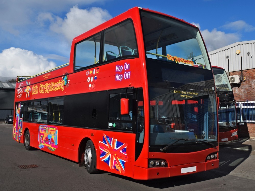 Fleet of tour buses with new red branded vehicle wraps and graphics for Bath Sightseeing.