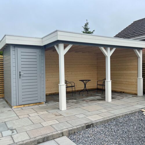 A bespoke garden gazebo supplied by Lugarde and designed and installed by Forevertimber. This stylish structure features a combination of an open-sided seating area and an enclosed storage room with a grey-painted door. The gazebo is constructed with white posts and cross-braced supports, complementing the light natural wood finish of the interior walls. It is built on a neatly paved base, providing a durable and clean surface. The open area is perfect for outdoor seating or dining, while the enclosed section offers additional functionality as a storage space. This design combines practicality with a modern, elegant aesthetic.