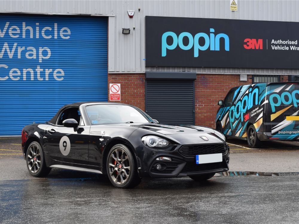 Motorsport graphics on a black Abarth 124 Spider sports car