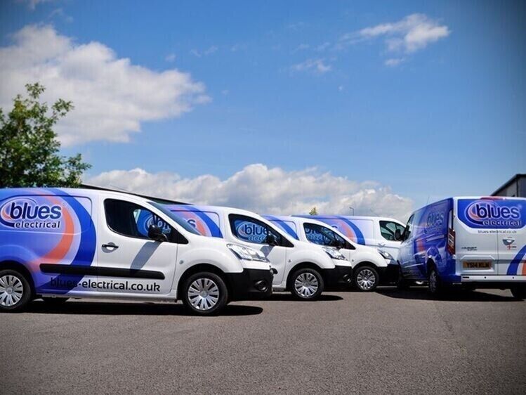 Fleet of company vans with identical branded vehicle wraps and graphics parked outside.
